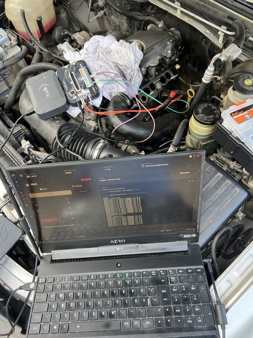 Opel Astra engine bay with Flex programmer reading the ECU