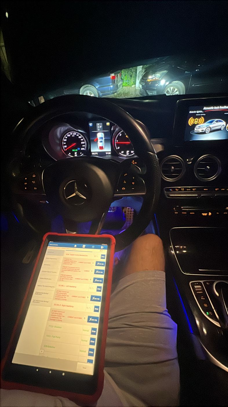 Diagnostic tablet reading fault codes inside a Mercedes at night