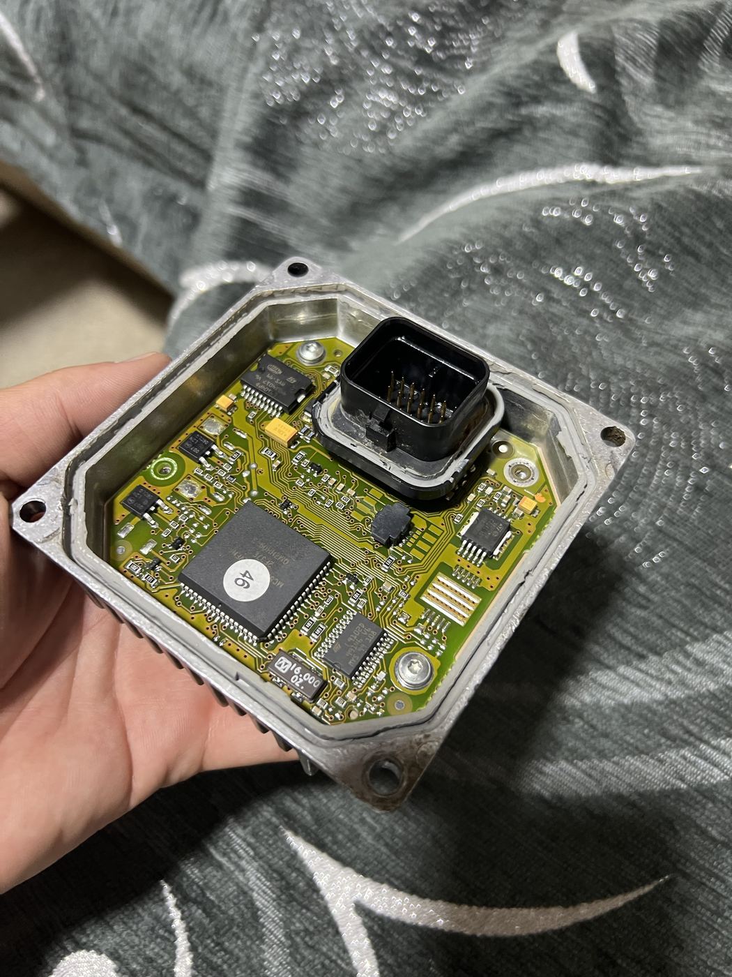 Opened transmission control unit circuit board held in hand