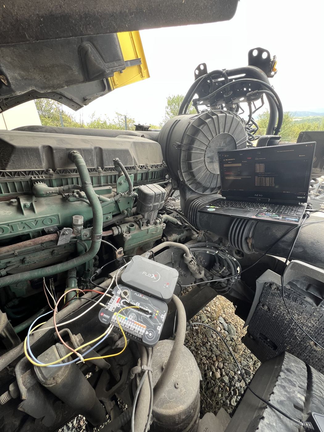 Volvo truck engine bay with a Flex programmer and laptop connected